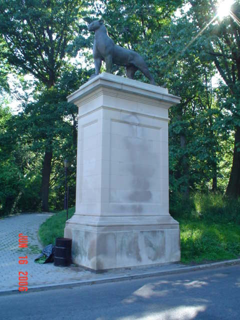 Two striding panthers on integral plinths, each on its own pedestal, framing the pedestrian entranceway