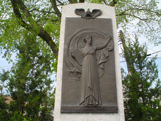 Bas-relief plaque with female figure (life size) surrounded by quotations; plaque is surmounted by an eagle with spread wings, on stele