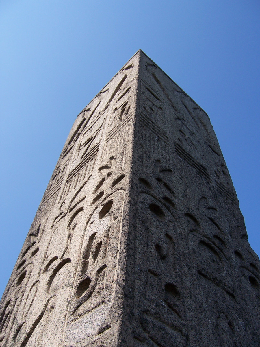 Obelisk supported by bronze crabs at four corners of base, on a block on a square terrace, plaques