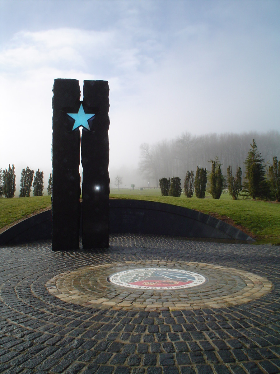 2-part granite column with star in the middle; paved plaza has semi-circular granite wall and inset mosaic design