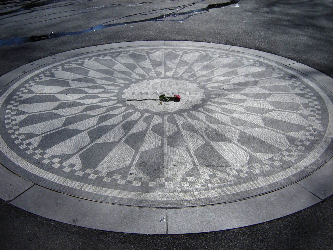 Mosaic roundel with starburst design set in pavement, plaque set in rock outcropping about a hundred yards east of roundel