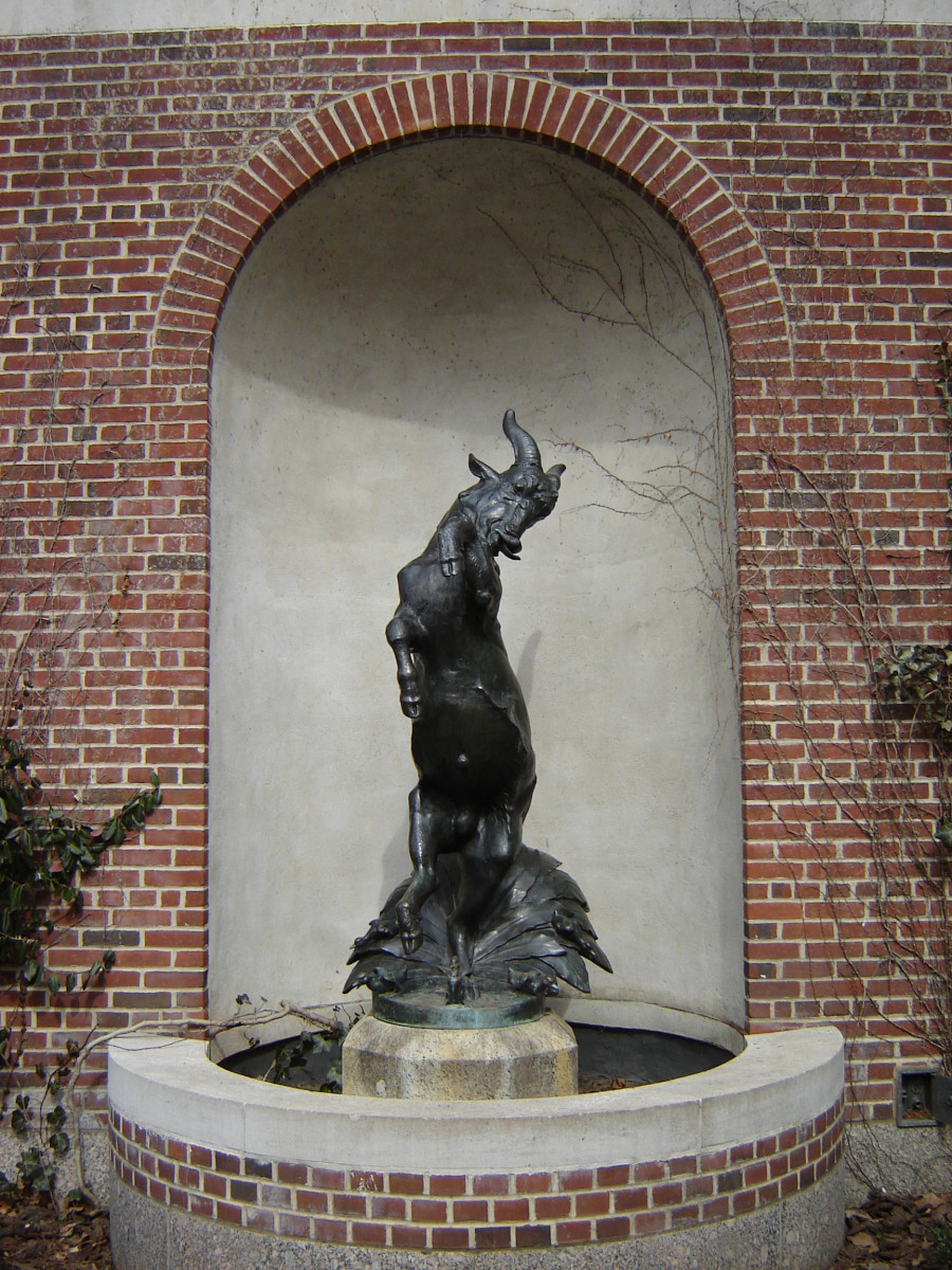 Goat standing on hind legs on integral plinth on pedestal in center of fountain basin