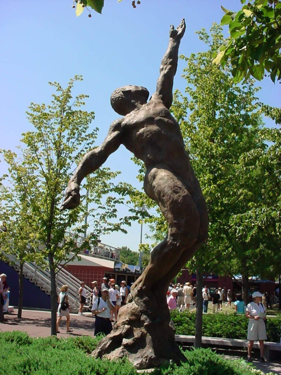 Standing male figure, left arm pointing upward, with integral plinth bolted to a plate on a footing, surrounded by a planting bed contained within low wall bearing inscriptions