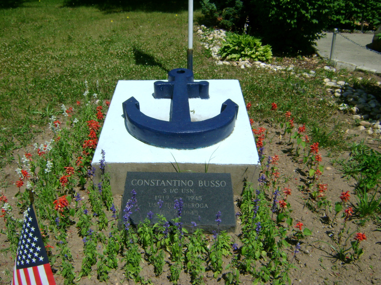 Two inscribed markers in ground in front of two cement plinths with blue anchors in relief