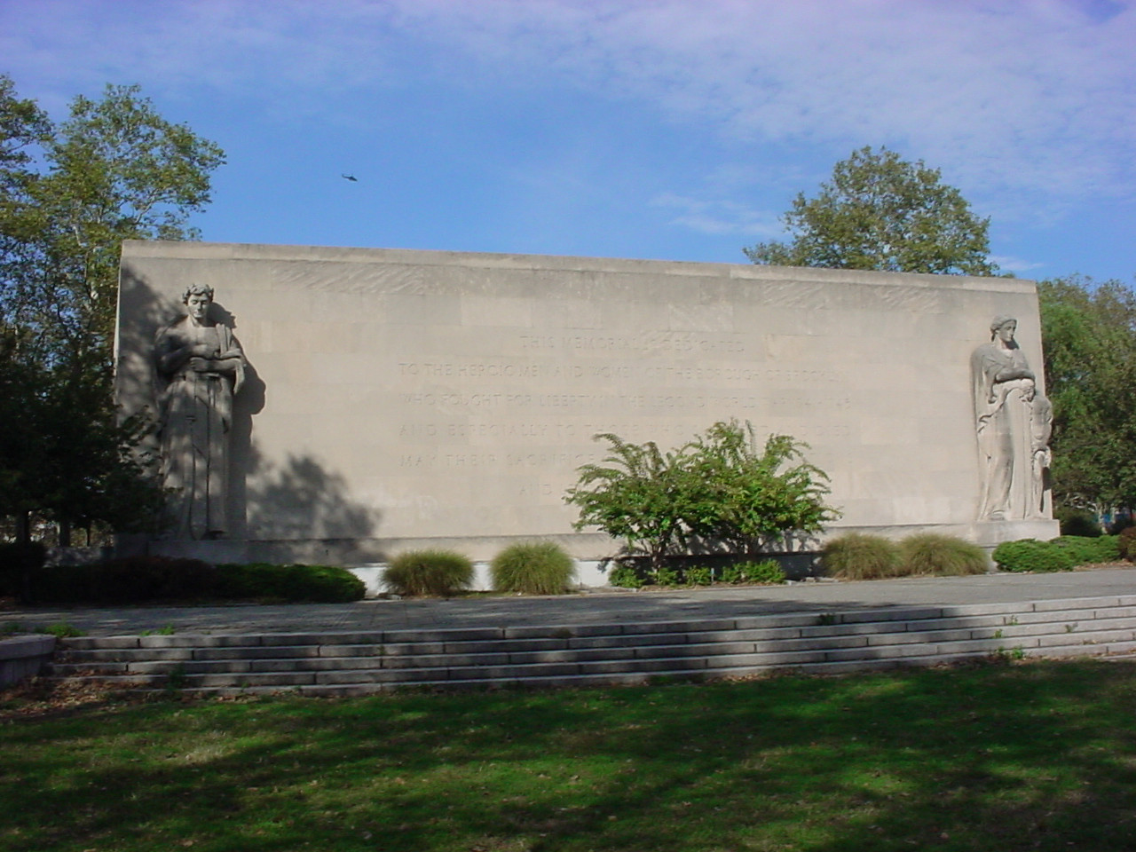 Building adorned by two large figures (heroic scale), one at either end of front façade