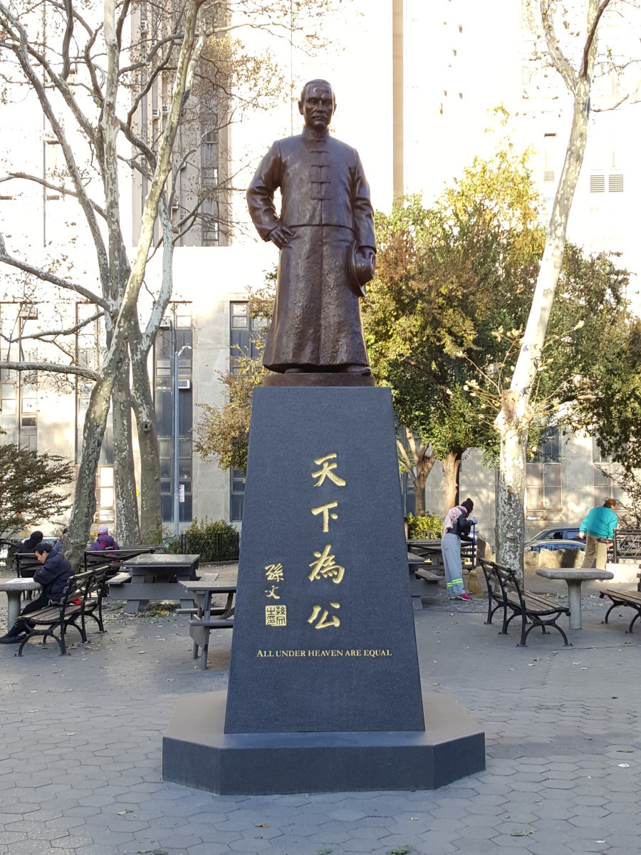 . Bronze figure (heroic size) of Dr. Sun Yat-sen;  proper left hand holding a hat. Granite pedestal, with inscription at middle of east and west  side.