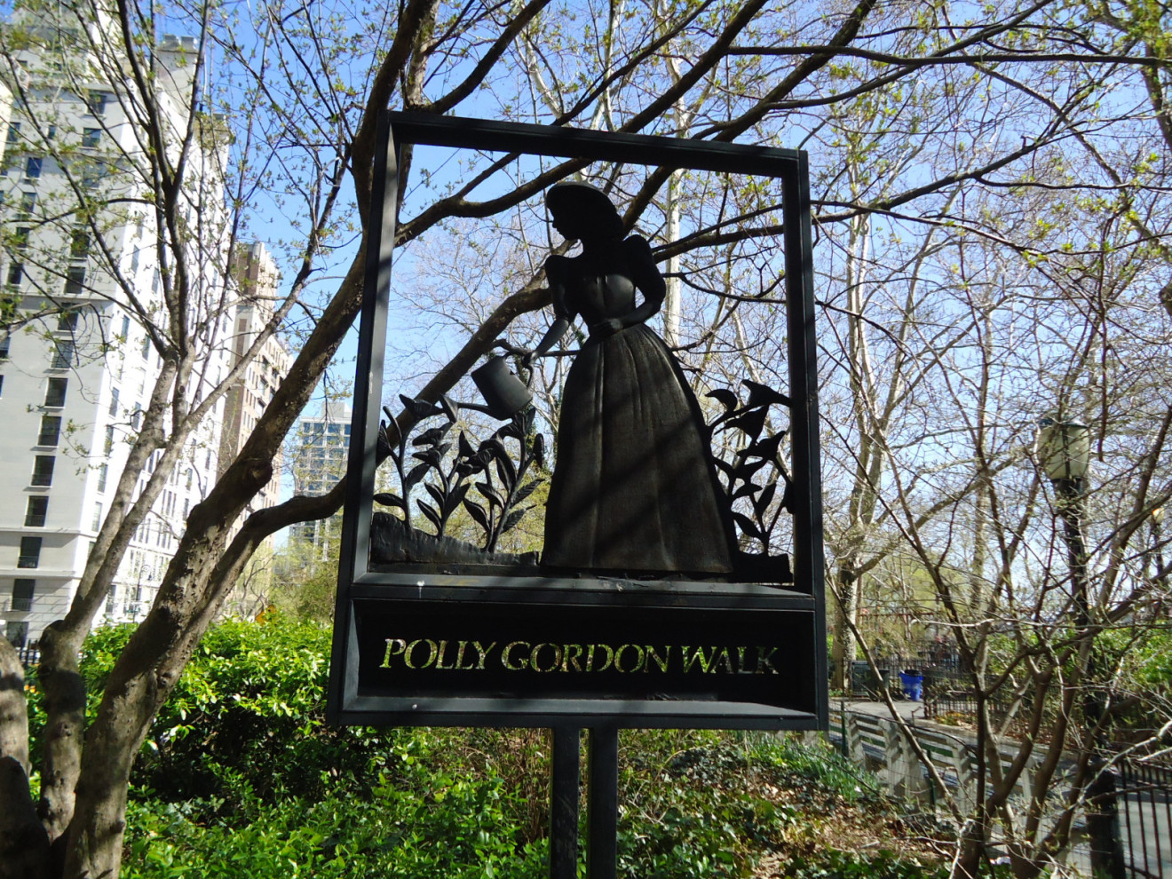 Cutout silhouette of woman watering flowers and name on pole