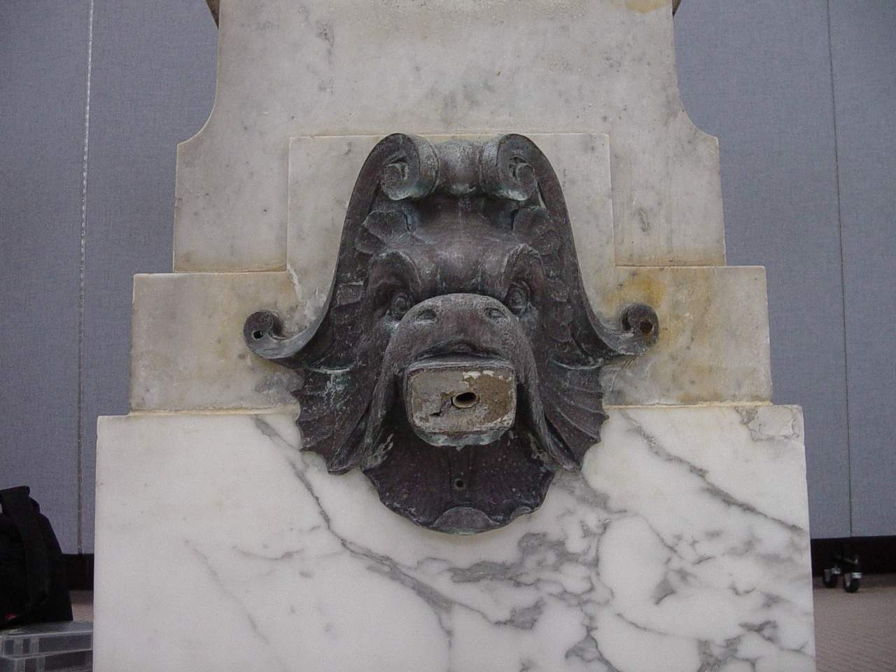 Dolphin head spout and stele, inside on pool deck