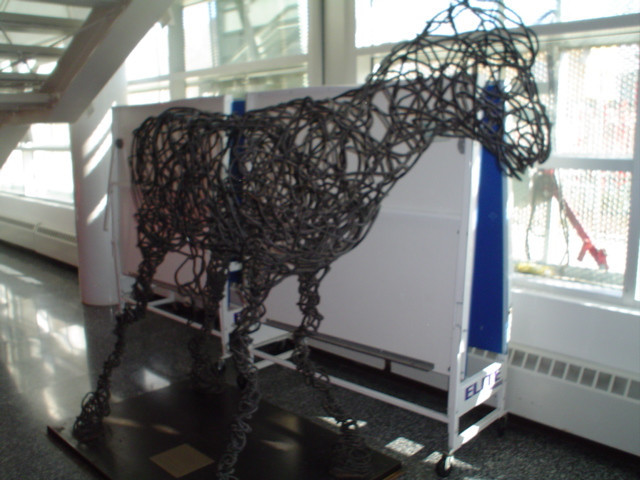 Sculpture of horse made out of a continuous piece of steel, on flat metal base