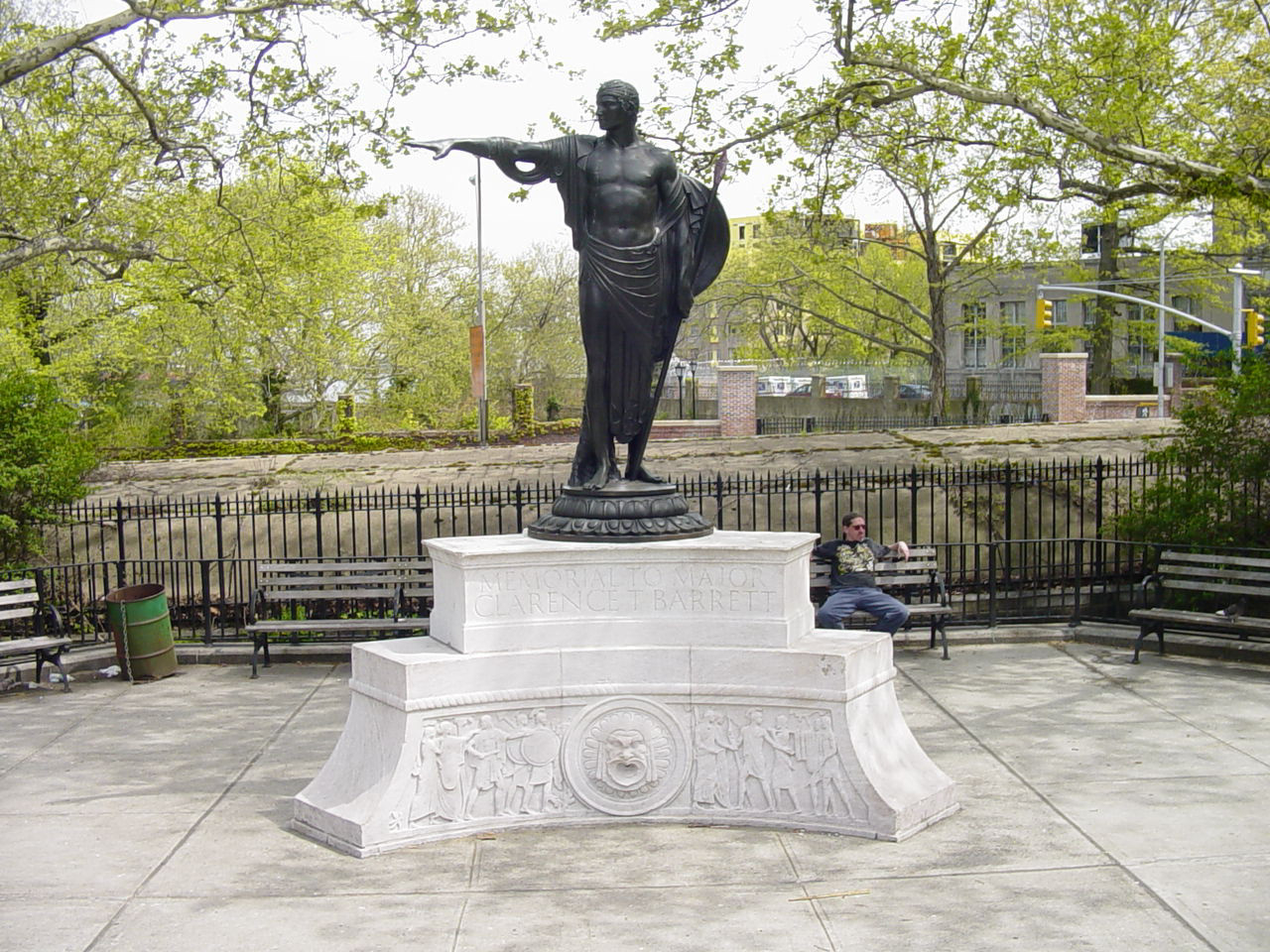 Standing figure with shield and spear (heroic scale) on integral plinth on broad, bilevel pedestal with bas-relief of two martial scenes separated by classical mask on lower level; large oval basin in front, and small drinking fountain in rear