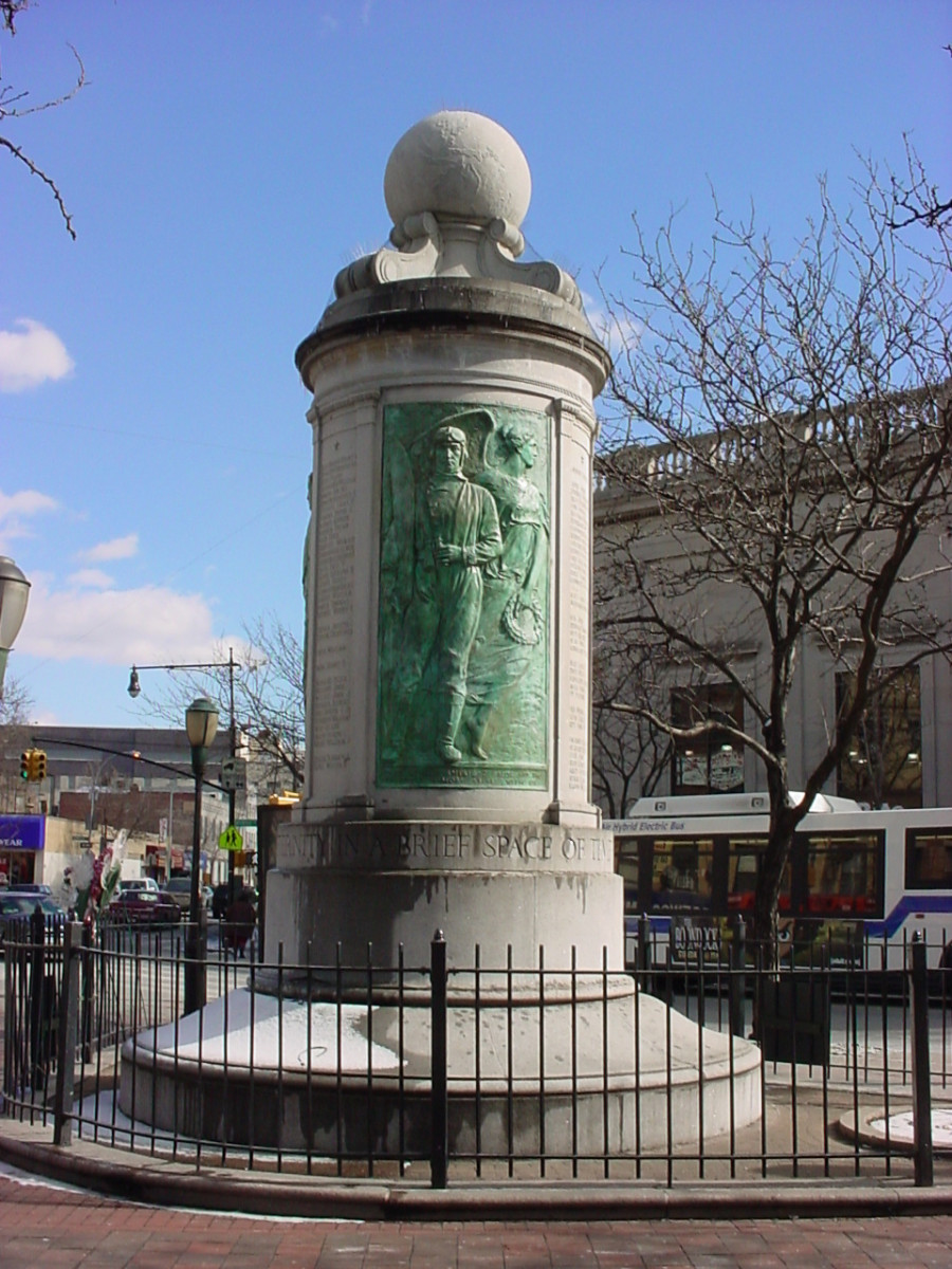 Column topped by a globe, on a circular base; column faced with three bas-reliefs; honor roll of names carved in spaces between the bas-reliefs