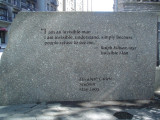 Sculpture; rectangular bronze structure with cut-out male figure; four engraved stone markers