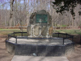 Boulder-like form (cairn) bearing a plaque, on a low base