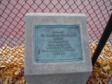 Bronze plaque on pillar with incised, green-painted leaf at bottom in pavement