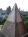 Obelisk supported by bronze crabs at four corners of base, on a block on a square terrace, plaques