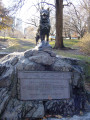 Canine figure on integral plinth on boulder with relief tablet mounted on front