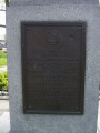 Standing figure (life size), on pedestal with four plaques