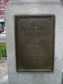 Standing figure (life size), on pedestal with four plaques