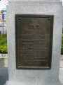 Standing figure (life size), on pedestal with four plaques