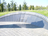 2-part granite column with star in the middle; paved plaza has semi-circular granite wall and inset mosaic design