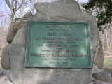 Boulder-like form (cairn) bearing a plaque, on a low base