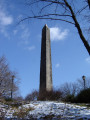 Obelisk supported by bronze crabs at four corners of base, on a block on a square terrace, plaques