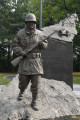 Over lifesized figure of soldier on mound, with separate mountainscape and honor-roll behind