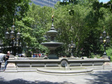 Square pool with candelabrum at each corner; central column consisting of circular basin with umbrella above, surmounted by fixture