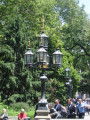 Square pool with candelabrum at each corner; central column consisting of circular basin with umbrella above, surmounted by fixture