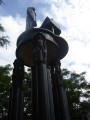 Standing figure (heroic scale) before a grand piano on a circular platform supported by three groups of three caryatids on three triform columns, integral plinth, two plaques on pedestal