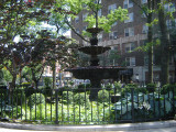 Ornamental fountain with three basins on base and catch basin below, fence