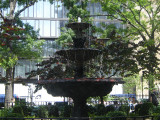 Ornamental fountain with three basins on base and catch basin below, fence