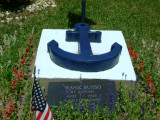 Two inscribed markers in ground in front of two cement plinths with blue anchors in relief