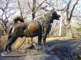 Canine figure on integral plinth on boulder with relief tablet mounted on front