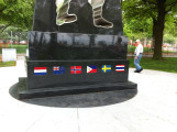 Obelisk with cutout in shape of soldier on base with mosaic flags, two plaques on two markers situated in circular plaza (axis aligned with Statue of Liberty)