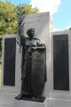 Standing figure with shield on integral plinth before stele; two tablets,