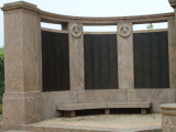 Group of two figures on pedestal before a high, arced wall; two benches; altar; six large plaques; one small plaque; paving