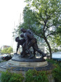 Group of three doughboy figures (over life-size) with integral plinth on a low base that rests on a circular pedestal; twenty plaques facing upward and carrying the names of the dead surround  the group