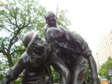 Group of three doughboy figures (over life-size) with integral plinth on a low base that rests on a circular pedestal; twenty plaques facing upward and carrying the names of the dead surround  the group