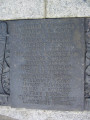 Group of three doughboy figures (over life-size) with integral plinth on a low base that rests on a circular pedestal; twenty plaques facing upward and carrying the names of the dead surround  the group