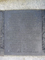 Group of three doughboy figures (over life-size) with integral plinth on a low base that rests on a circular pedestal; twenty plaques facing upward and carrying the names of the dead surround  the group