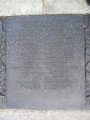 Group of three doughboy figures (over life-size) with integral plinth on a low base that rests on a circular pedestal; twenty plaques facing upward and carrying the names of the dead surround  the group