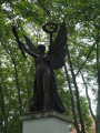 Standing angel figure (over life-size) holding a laurel wreath in her left hand and a palm bough in her right,, on integral plinth on pedestal