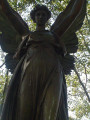 Standing angel figure (over life-size) holding a laurel wreath in her left hand and a palm bough in her right,, on integral plinth on pedestal