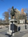 Figure (heroic scale) on integral plinth, pedestal with four recessed relief plaques