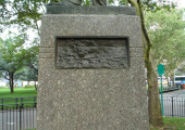 Figure (heroic scale) on integral plinth, pedestal with four recessed relief plaques