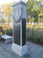 Inscribed cenotaph with three large plaques (one broad, two narrow), one medium plaque, and seven small plaques; fountain; two benches