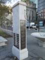 Inscribed cenotaph with three large plaques (one broad, two narrow), one medium plaque, and seven small plaques; fountain; two benches