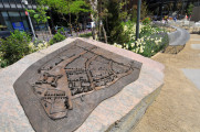 Three-dimensional plaque on natural boulder; nine narrative stones in pavement