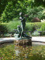 Standing girl figure and reclining boy figure on pedestal; tablet in pavement